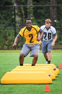 Jaquez Parks (gold jersey) and Taylor Henkle (white jersey) weave through hurdles in the football program's inaugural workout on Tuesday.