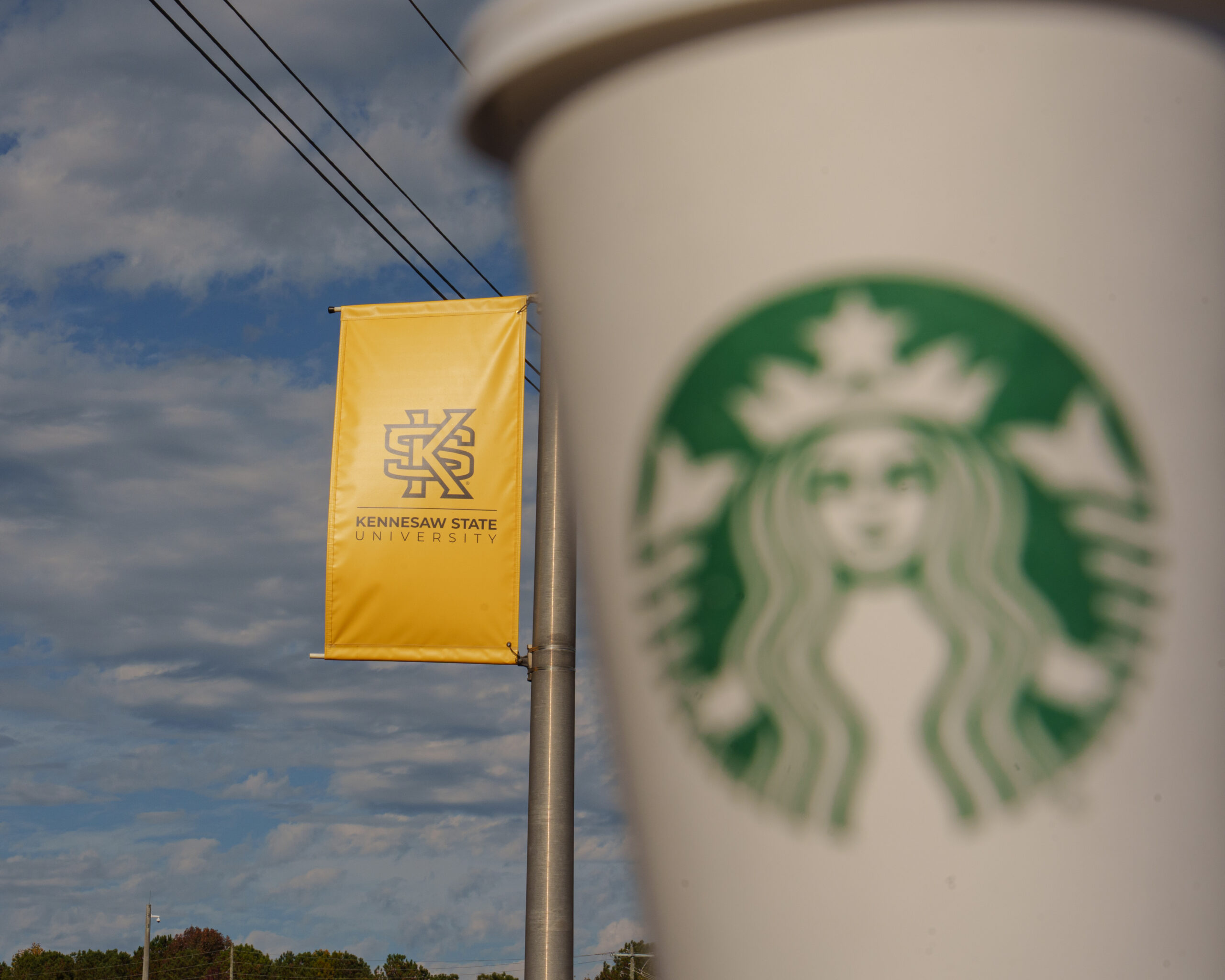 Starbucks cup posed in front of KSU sign.