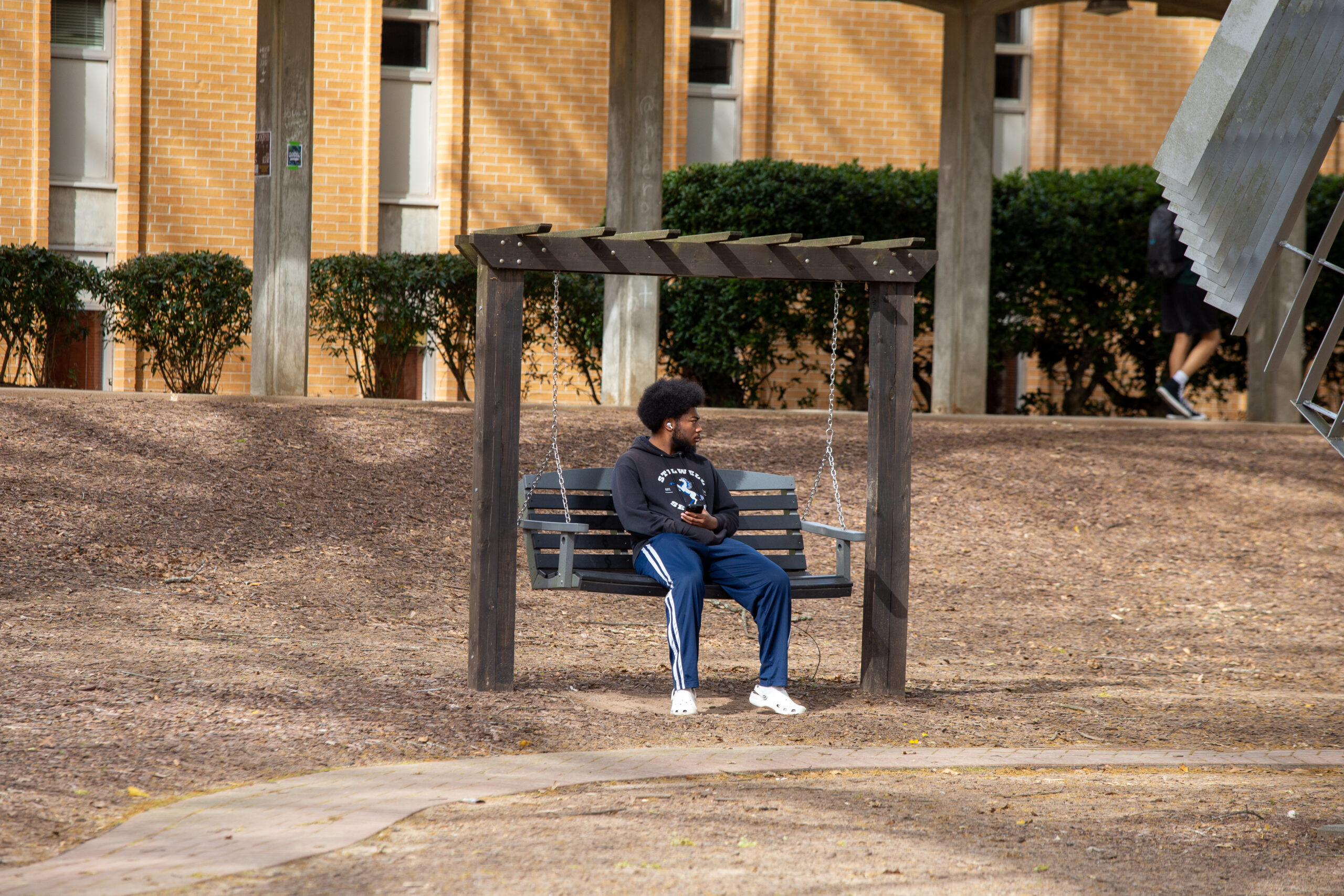 Student enjoying the swing bench near the Social Sciences Building.