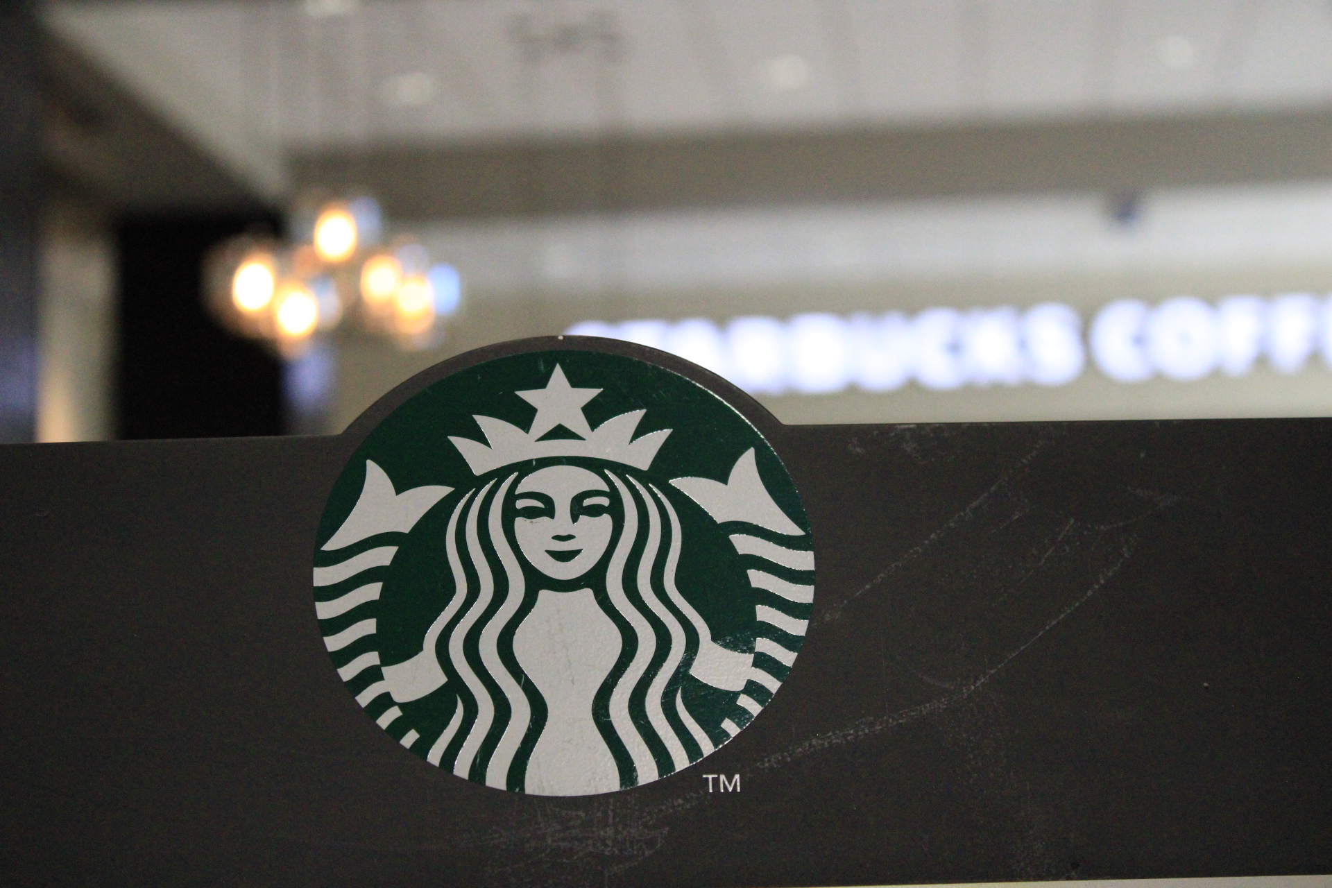 Starbucks logo with the front of the store in the background.