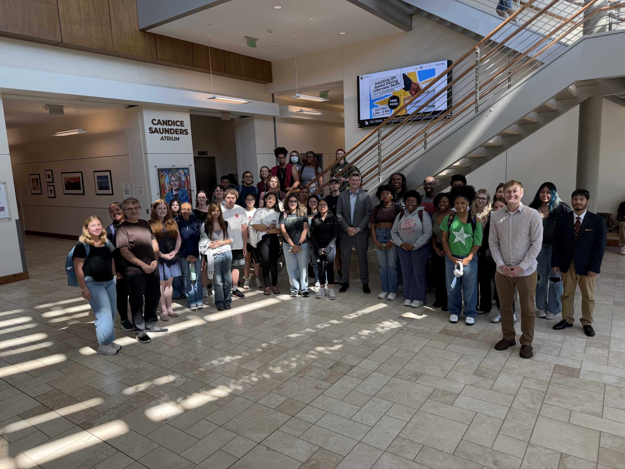 Students gather around Greg Bluestein in the prillaman building for a photo